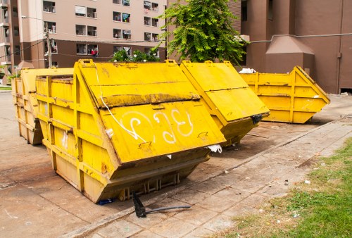Branded skip hire vehicle and staff in high-visibility clothing at site entrance