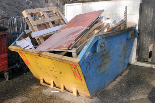Workers wearing PPE handling waste near a skip